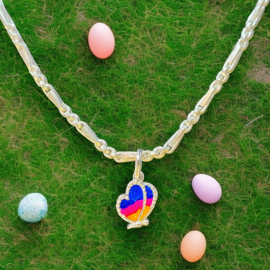 Necklace with a colorful heart-shaped pendant on a green surface with Easter eggs.